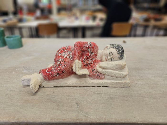 Eine liegende und lesende Frau in Rotem Kleid