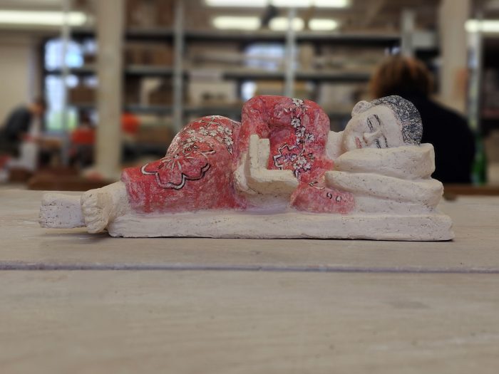 Eine liegende und lesende Frau in Rotem Kleid